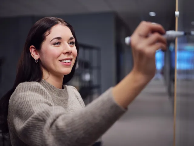 Young woman writing on a whiteboard smiling