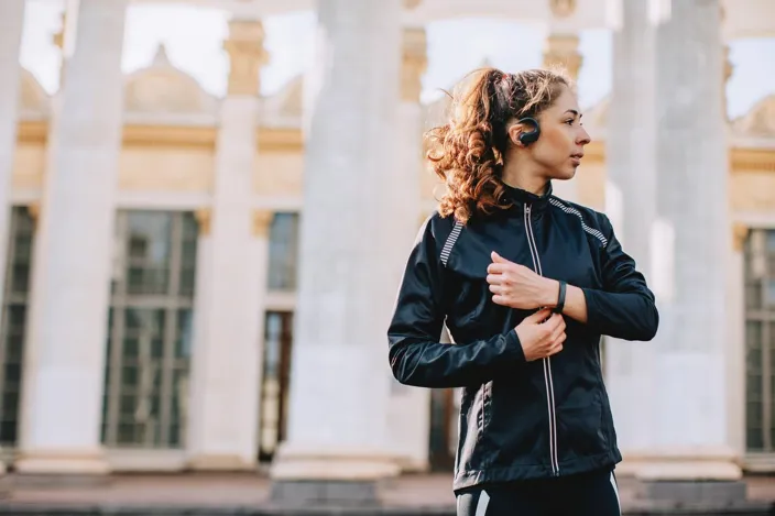 Young female athlete listening to music outdoors