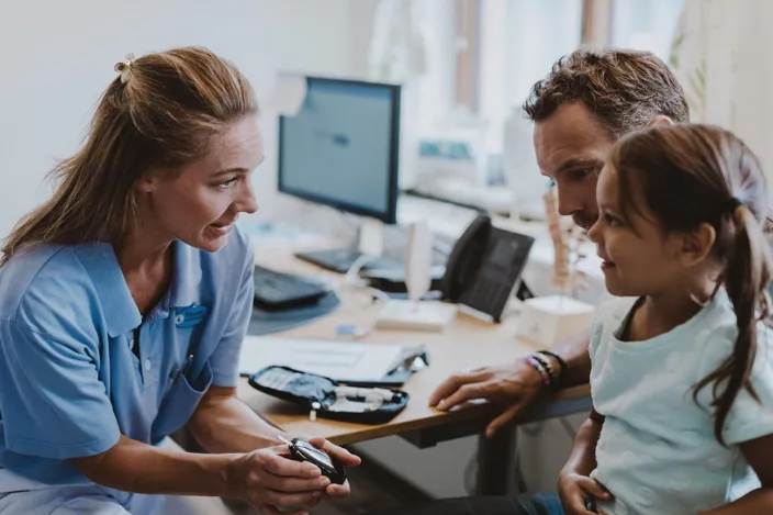 Woman doctor, nurse talking to a young girl patient and showing her medical device